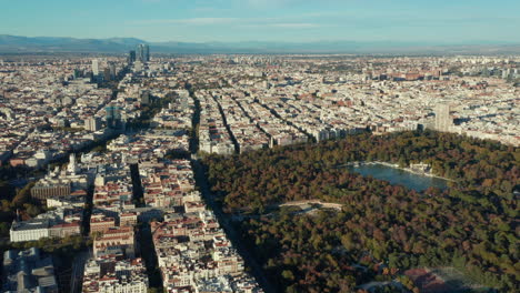 Aerial-panoramic-footage-of-large-metropolis.-Blocks-of-buildings-separated-by-streets.-Big-green-El-Retiro-park-with-sights-and-water-surface.