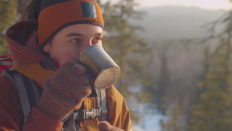female tourist drinking hot tea during winter hike