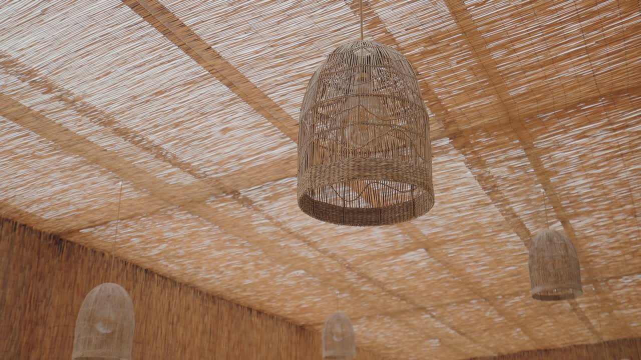 Soffitto a baldacchino in canne con lampade a sospensione in vimini sopra un'area salotto esterna