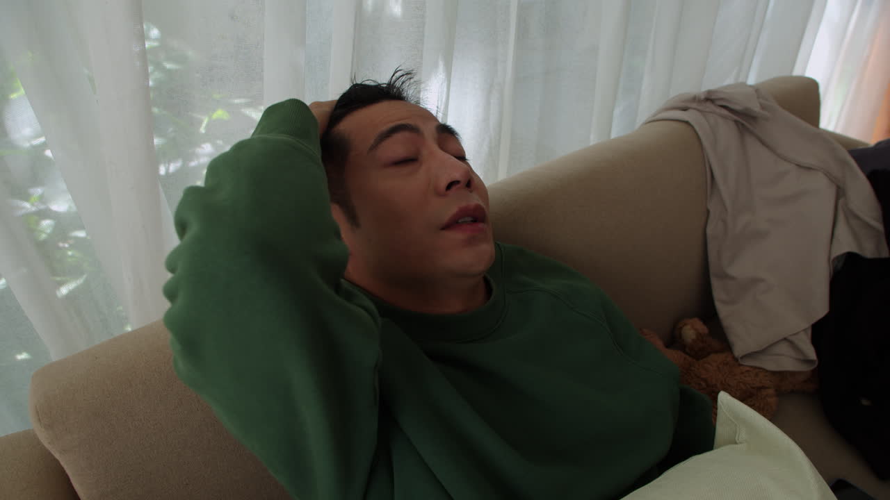 소파에 누워 있는 슬픈 남자