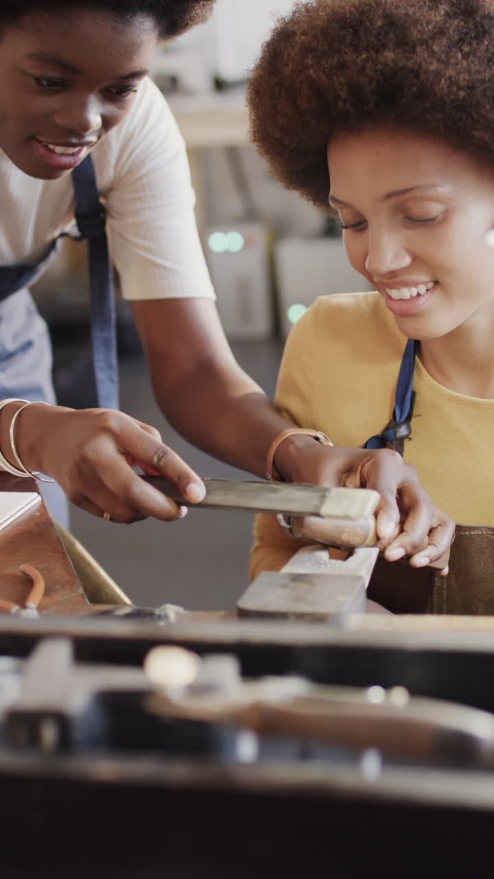 Vertical video of diverse female workers shaping ring in workshop in slow motion