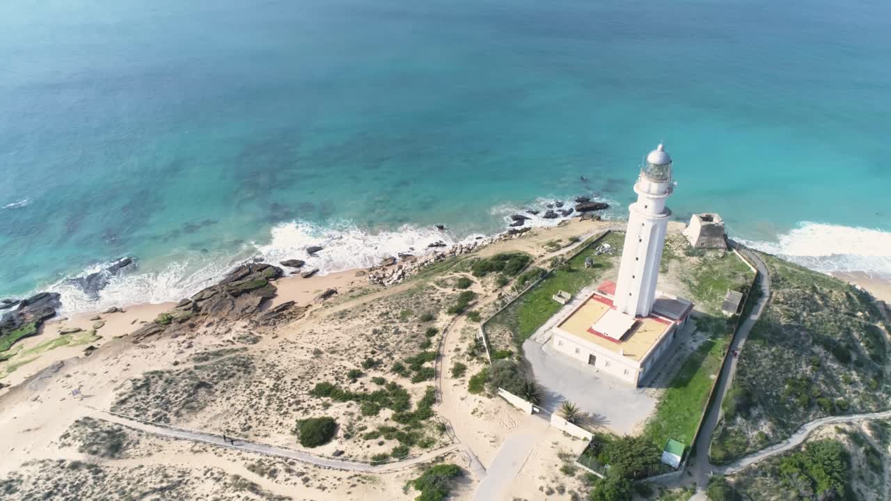 vista aérea de un faro junto a un mar en calma en un día soleado