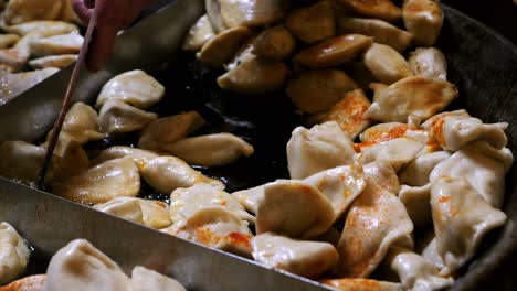 street food. chef cooking polish dish - pierogi, preparing them by frying in hot oil in a large skillet