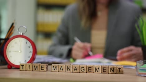 time management word blocks with alarm clock and person working