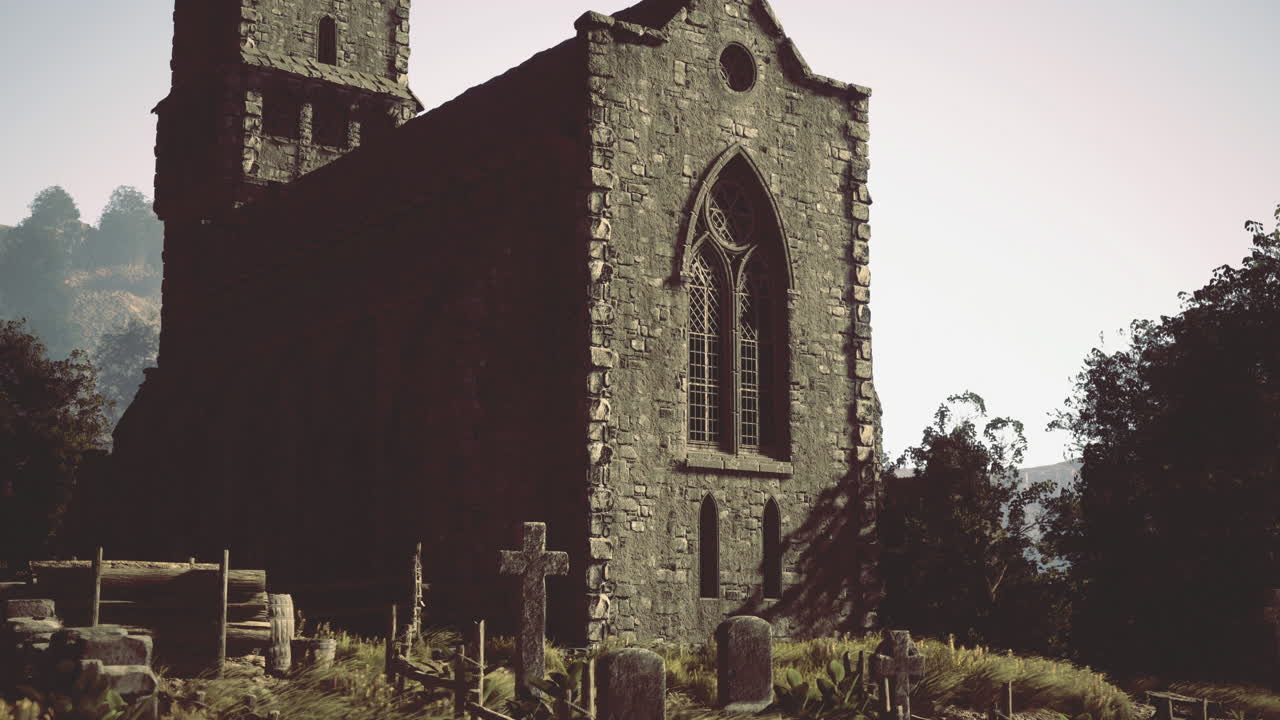 Old stone church stands amidst graves in a serene landscape at sunset