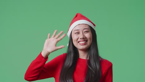 woman wearing santa hat waving
