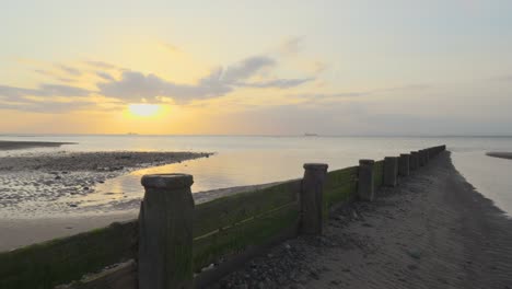 Approaching-breakwater-with-ships-on-horizon-on-calm-sea-during-sunset-in-slow-motion-at-Fleetwood,-Lancashire,-UK