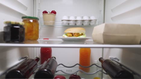 woman searching for food in the fridge at night