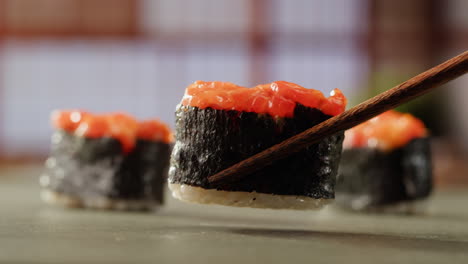 close-up of salmon sushi rolls with chopsticks