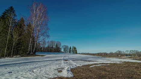 Sun-and-clouds-moving-quickly-over-snow-covered-field-in-rural-nordic-landscape