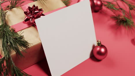 video of christmas decorations and white card with copy space on red background