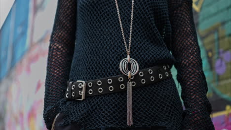 close up outdoor fashion shot showing clothes jewellery and accessories of alternative style woman against graffiti covered wall in london city street uk in real time