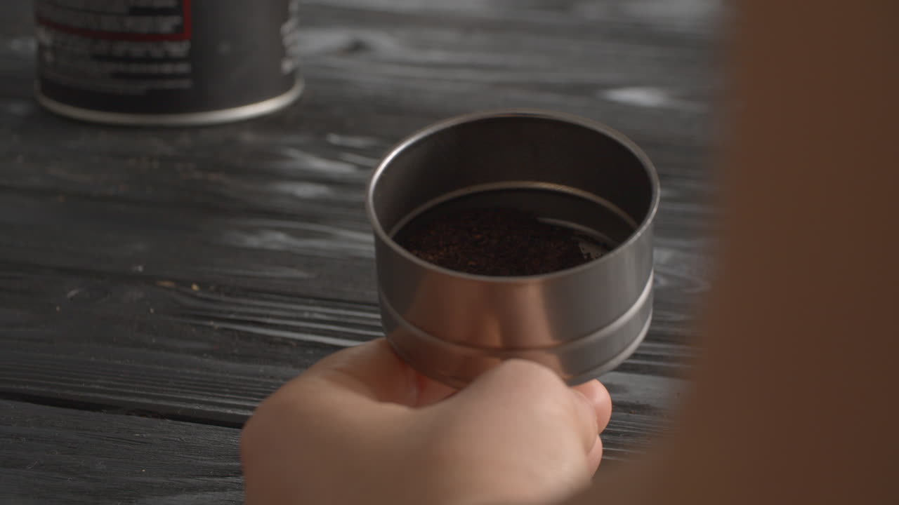 женщина наполняет воронку кастрюли с кофе.