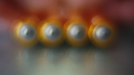 video macro de una pila de baterías rodantes en un escritorio con reflejo, batería dorada, cámara lenta 120 fps, full hd, revela movimiento suave