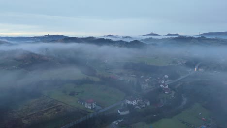 mist hovering over hilly village countryside landscape at dawn, italy