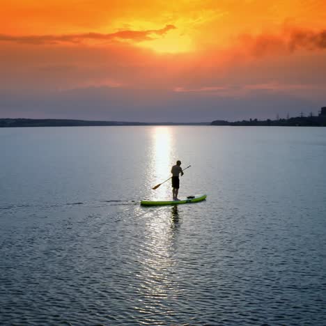stand up paddle boarding. handsome young man standing on sup board