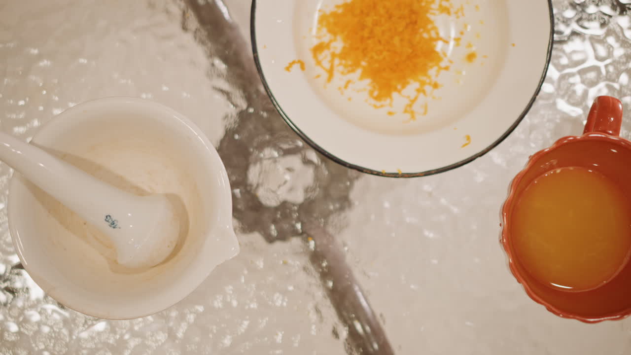 Closeup pumpkin pie ingredients glass table orange zest on plate, small red cup with yolk, white mortar and pestle, textured glass surface, warm intimate kitchen prep, calm autumn atmosphere