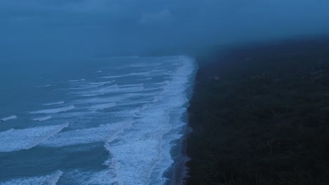 aerial view of ocean waves reaching the coastline and the jungle of pacific beach in colombia on summer day