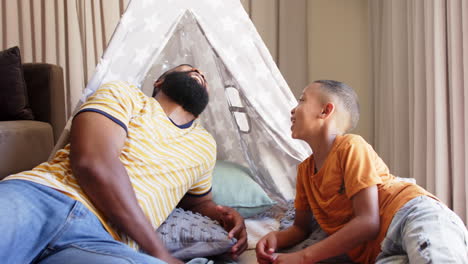 african american father and young son playing together in cozy indoor tent