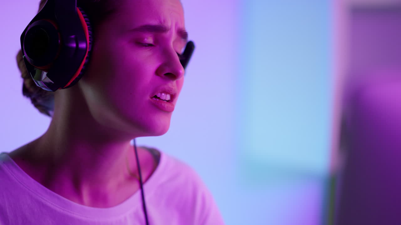 Nærbilde av trist jente som taper cyber-spill i neonlys. Lei student som stryker på prøver.