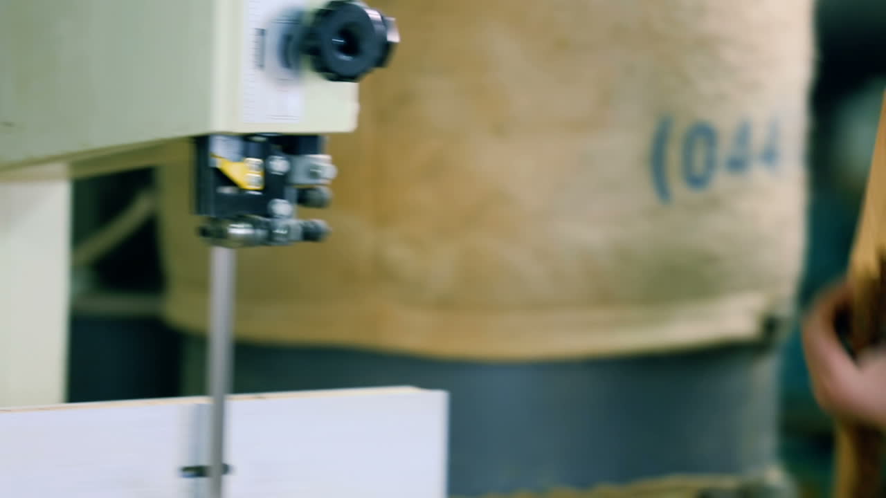 Electric Fret Saw For Cutting Wood. Hands of a skilled craftsman cutting a wooden plank with a saw in a workshop