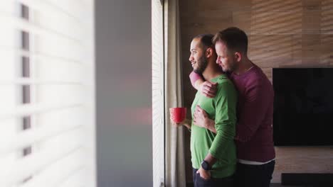 Multi-ethnic-gay-male-couple-drinking-coffee-and-embracing