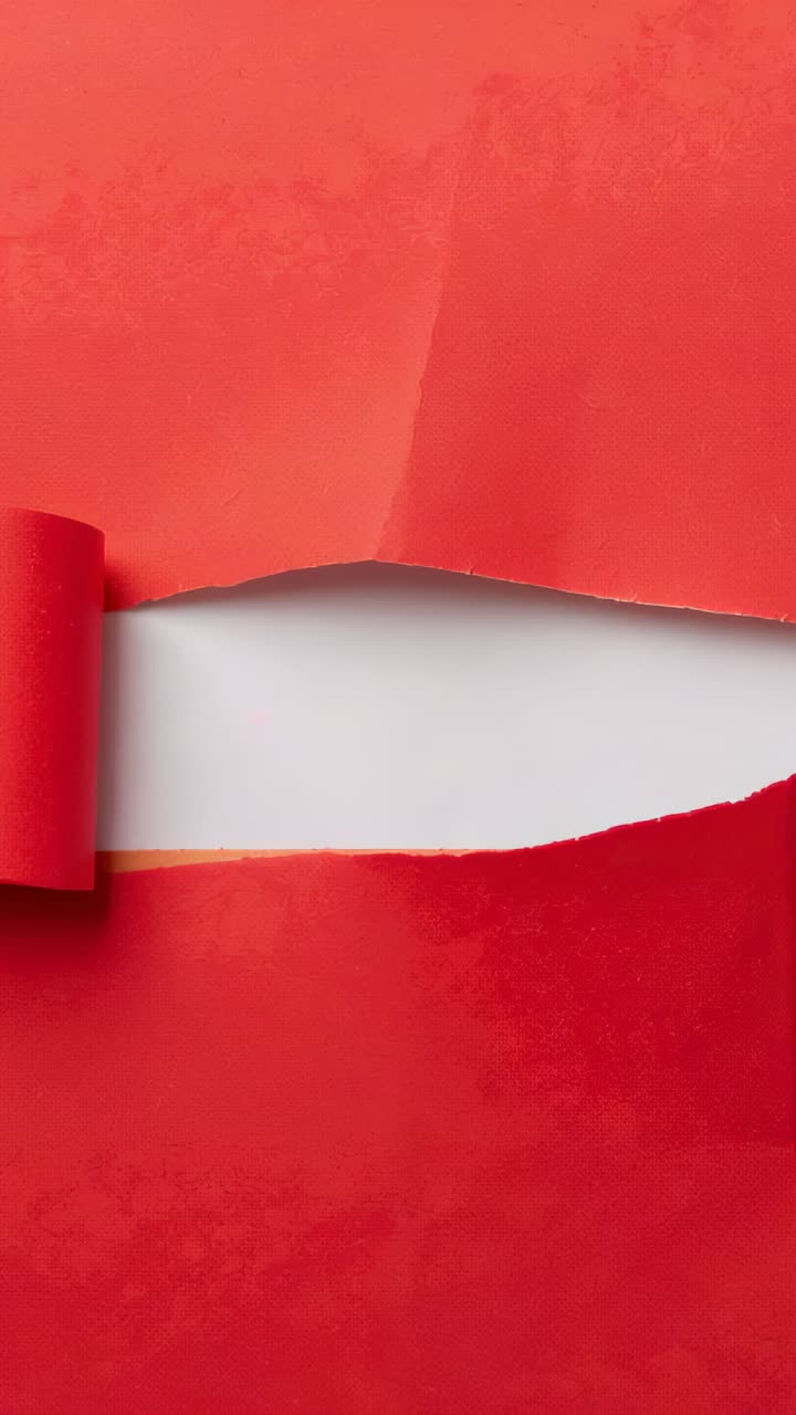 Vídeo vertical: papel vermelho rasgado no topo, revelando o lado branco em uma mesa de estúdio, com aba enrolada