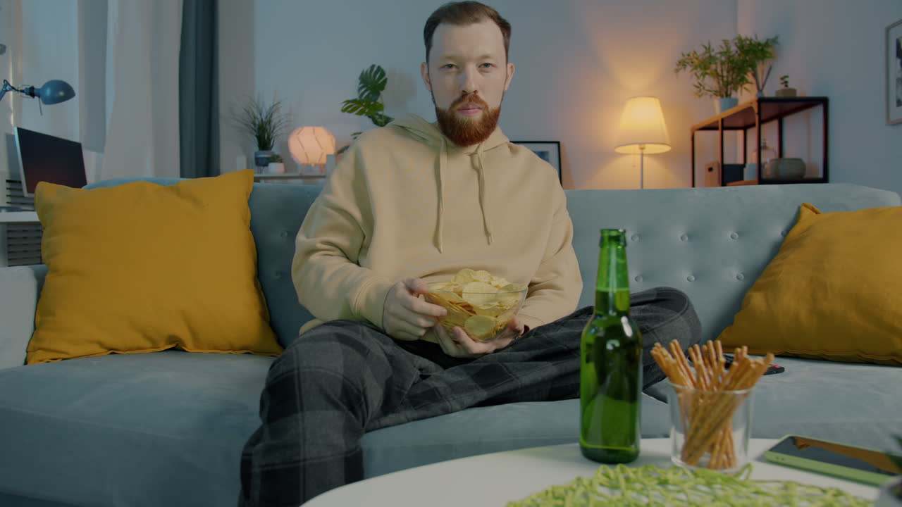Man Relaxing on Couch with Beer and Chips