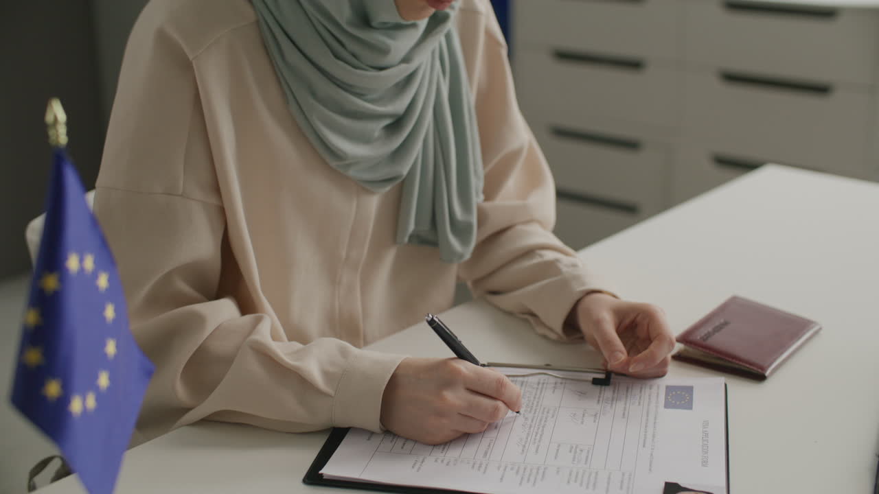 Muslim Woman Filling Out EU Visa Application Form at Desk