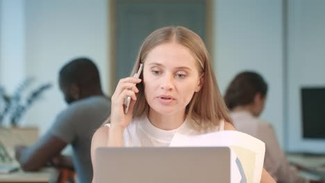 Mujer-Agresiva-Hablando-Por-Teléfono-En-Coworking.-Primer-Plano-Mujer-Enojada-Agitando-Papeles.