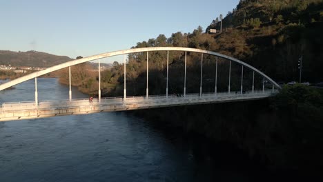 Aerial-shot-over-a-bridge-with-pedestrians-walking-on-it-in-the-River-Miño-in-Spain