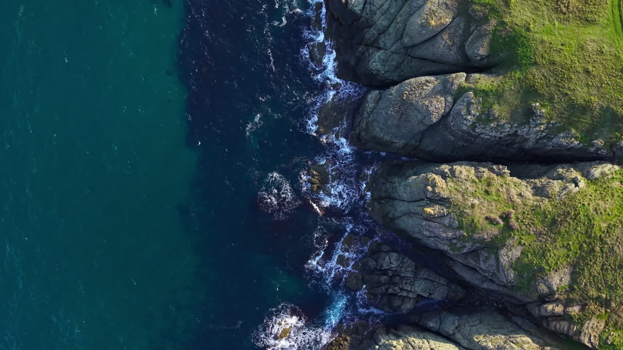 Le onde si infrangono contro scogliere frastagliate mentre i gabbiani danzano sopra il mare tranquillo, creando una serena scena costiera durante l'ora d'oro