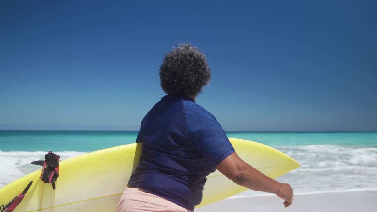 Senior woman walking with surfboard