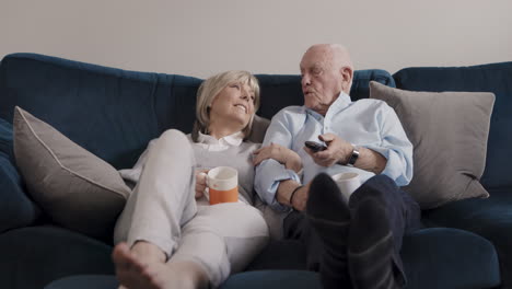 elderly couple relaxing on couch watching television