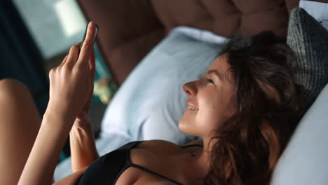 una mujer bonita arrojando un teléfono móvil a la cama.