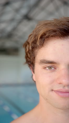 Vertical video: Smiling young man standing by swimming pool, looking confident and relaxed