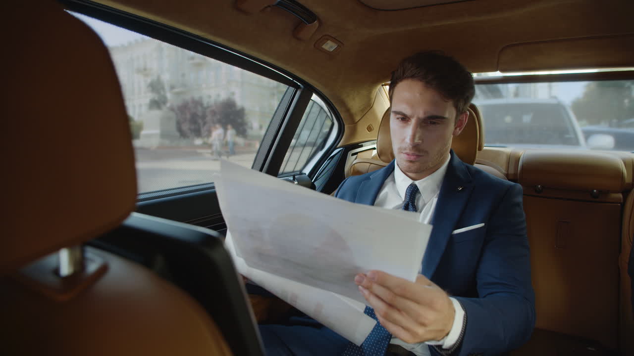 elegante hombre de negocios revisando estadísticas en el papeleo en un coche moderno.