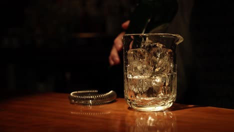 bartender pouring whiskey into ice-filled glass