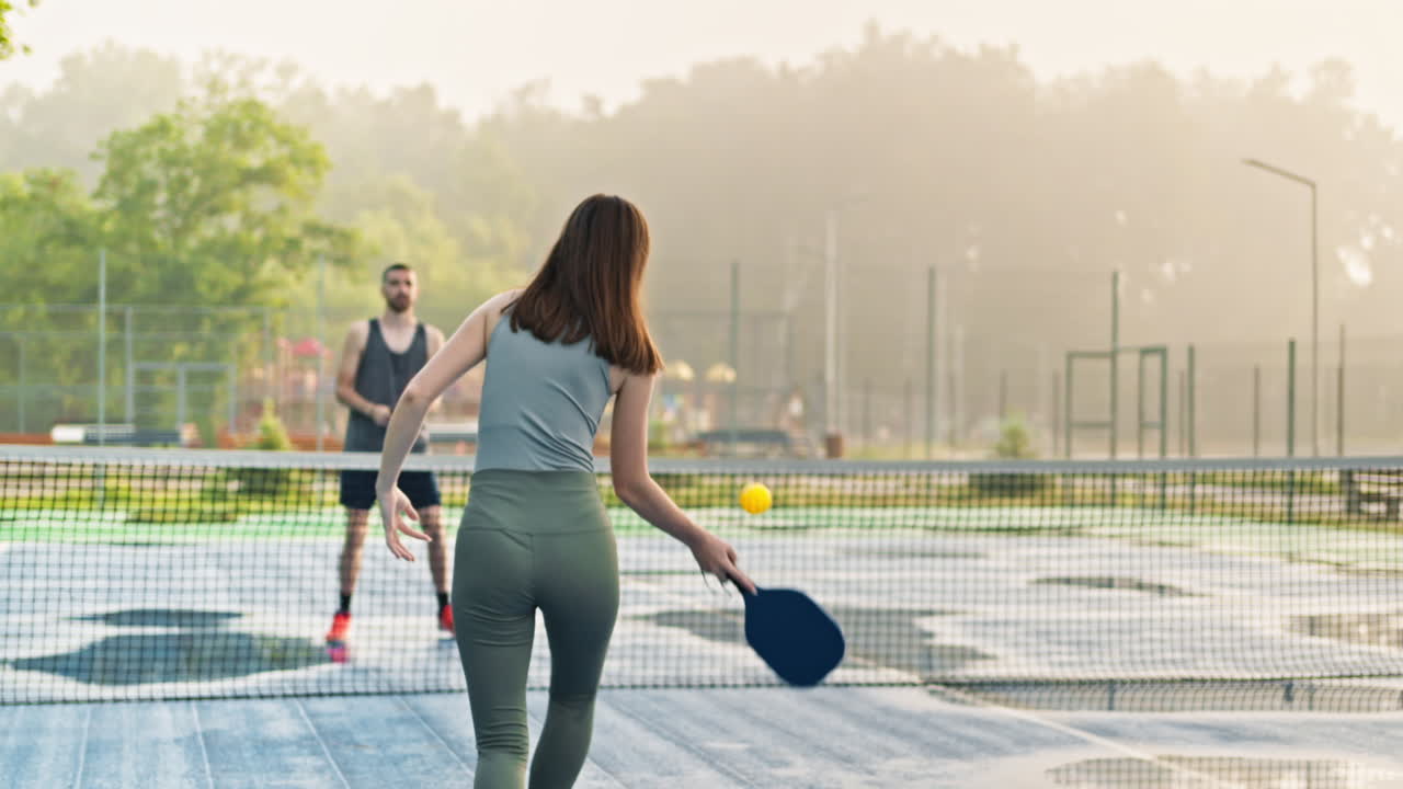 A man and a woman playing pickleball after rain