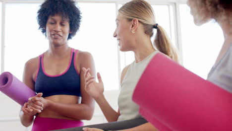 grupo diverso de amigos sosteniendo esteras de yoga y hablando