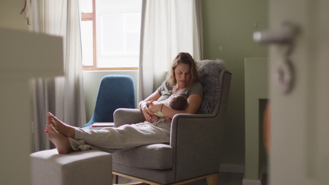 video de una madre caucásica feliz alimentando a un recién nacido en un sillón