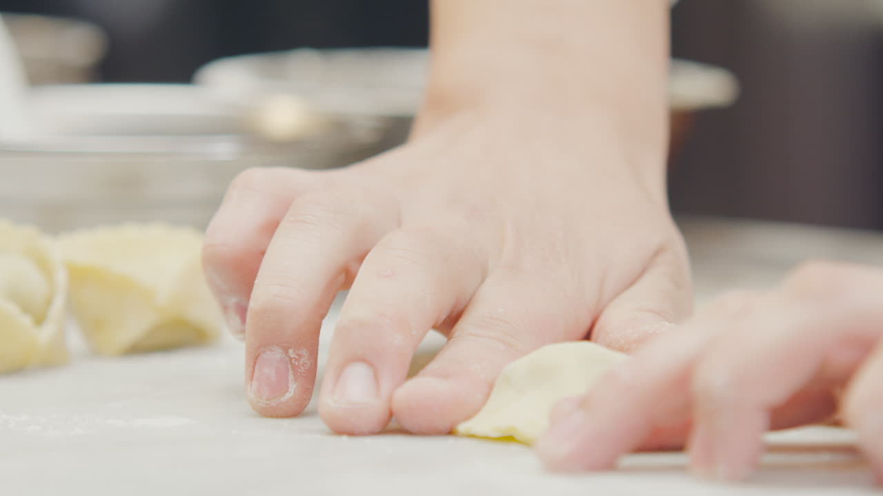 Chef's hands shaping filled ravioli with artisanal technique in a professional kitchen
