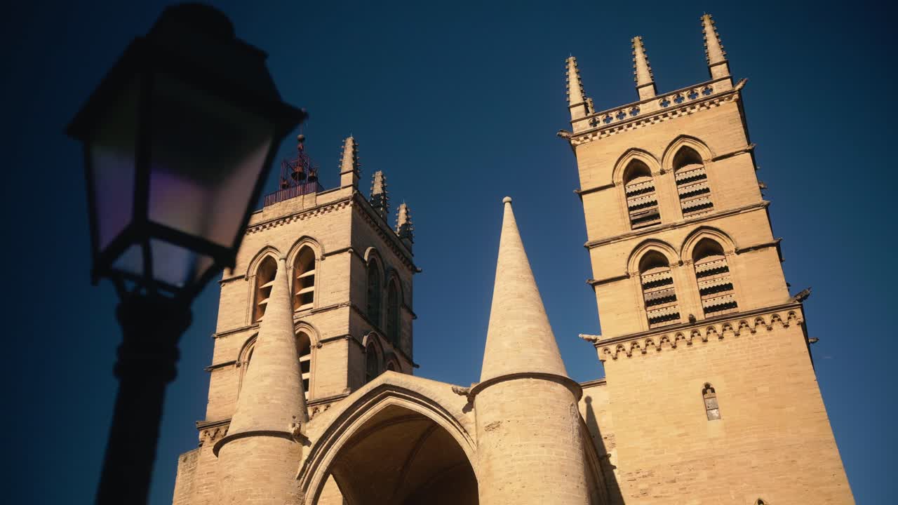 Ripresa dal basso dei campanili di una cattedrale con la silhouette di un lampione