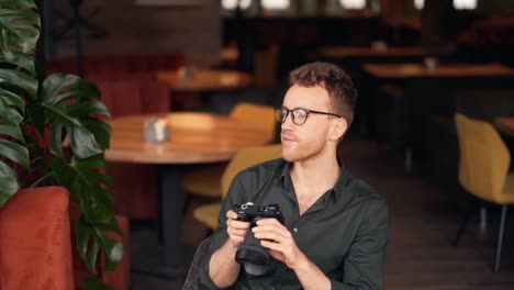 cute young man with a camera in a cafe looking at a photo