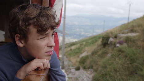 teenager looking out at a mountain view from a train window