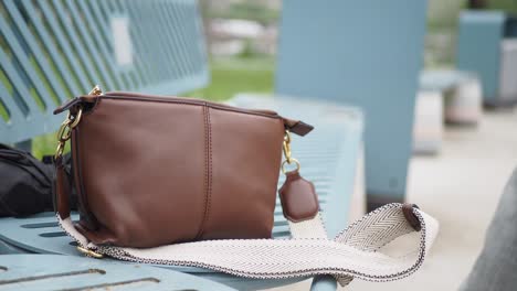 brown leather crossbody bag on a bench