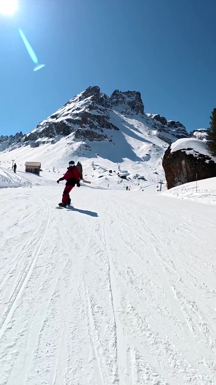 Snowboarder and Skier Descending Sunny Mountain Slope