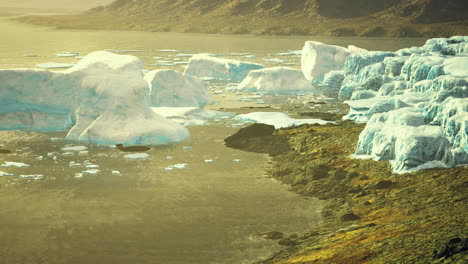glacial landscape with melting icebergs at sunset near a rocky shore