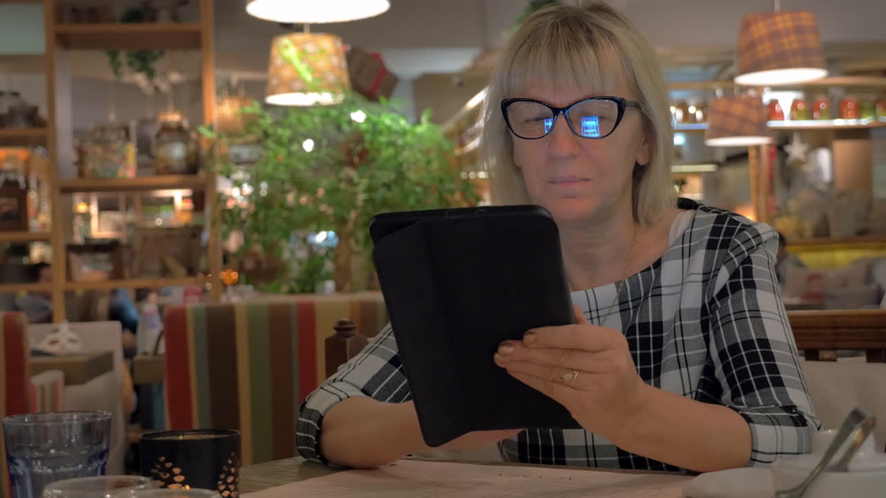 Senior woman surfing internet on pad in cafe