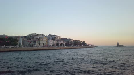 Evening,-cinematic-slow-mo,-the-view-of-uskudar-and-the-adjacent-Maiden's-Tower-from-a-ferry-sailing-along-the-Istanbul-Bosphorus